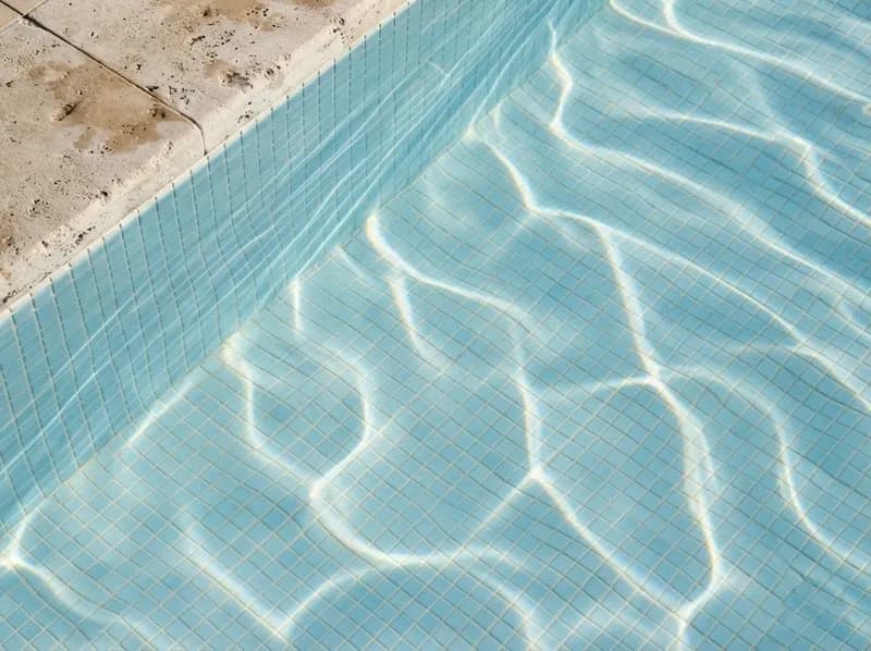 Água de piscina cristalina com reflexos de sol nos azulejos do fundo